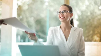 Confident woman smiling and accepting a document in a bright office environment