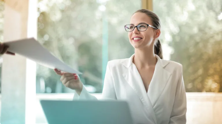 Confident woman smiling and accepting a document in a bright office environment