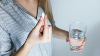 Person holding a pill and glass of water, preparing to take anxiety medication