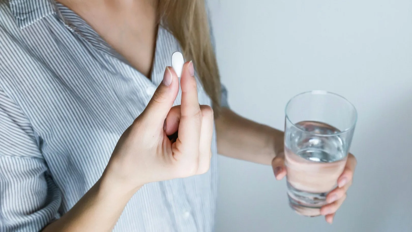 Person holding a pill and glass of water, preparing to take anxiety medication