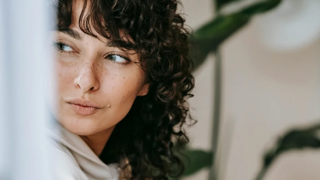 Pensive woman looking out with a thoughtful expression, symbolizing deep focus and emotional processing in brainspotting and EMDR therapy
