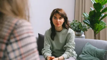 Young woman sitting on a couch during therapy session, representing trauma therapy alternatives to EMDR at Bright Spot Counseling