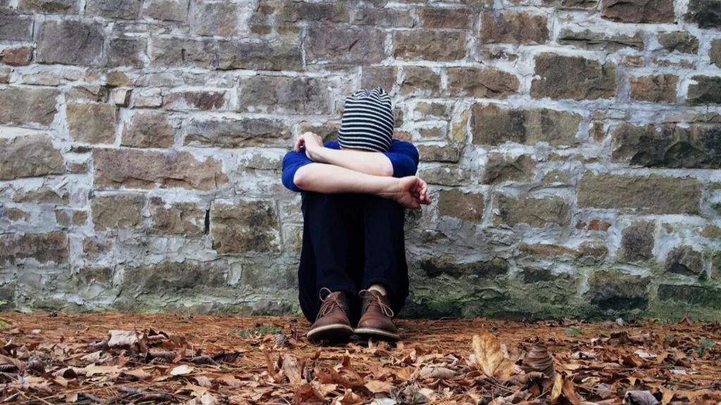 Teen sitting alone against a wall, struggling with rejection sensitivity dysphoria in Michigan