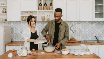 Couple cooking together in a modern kitchen, pouring milk and whisking batter as a shared activity