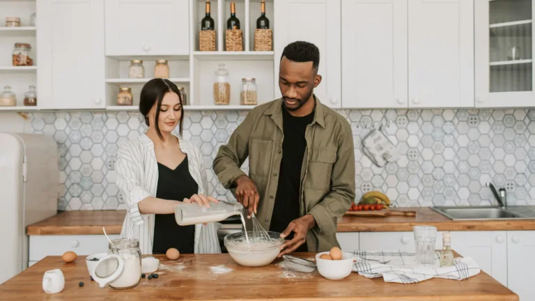 Couple cooking together in a modern kitchen, pouring milk and whisking batter as a shared activity
