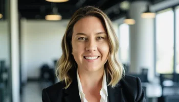 Professional headshot of female therapist in a business suit, smiling in a well-lit office setting.
