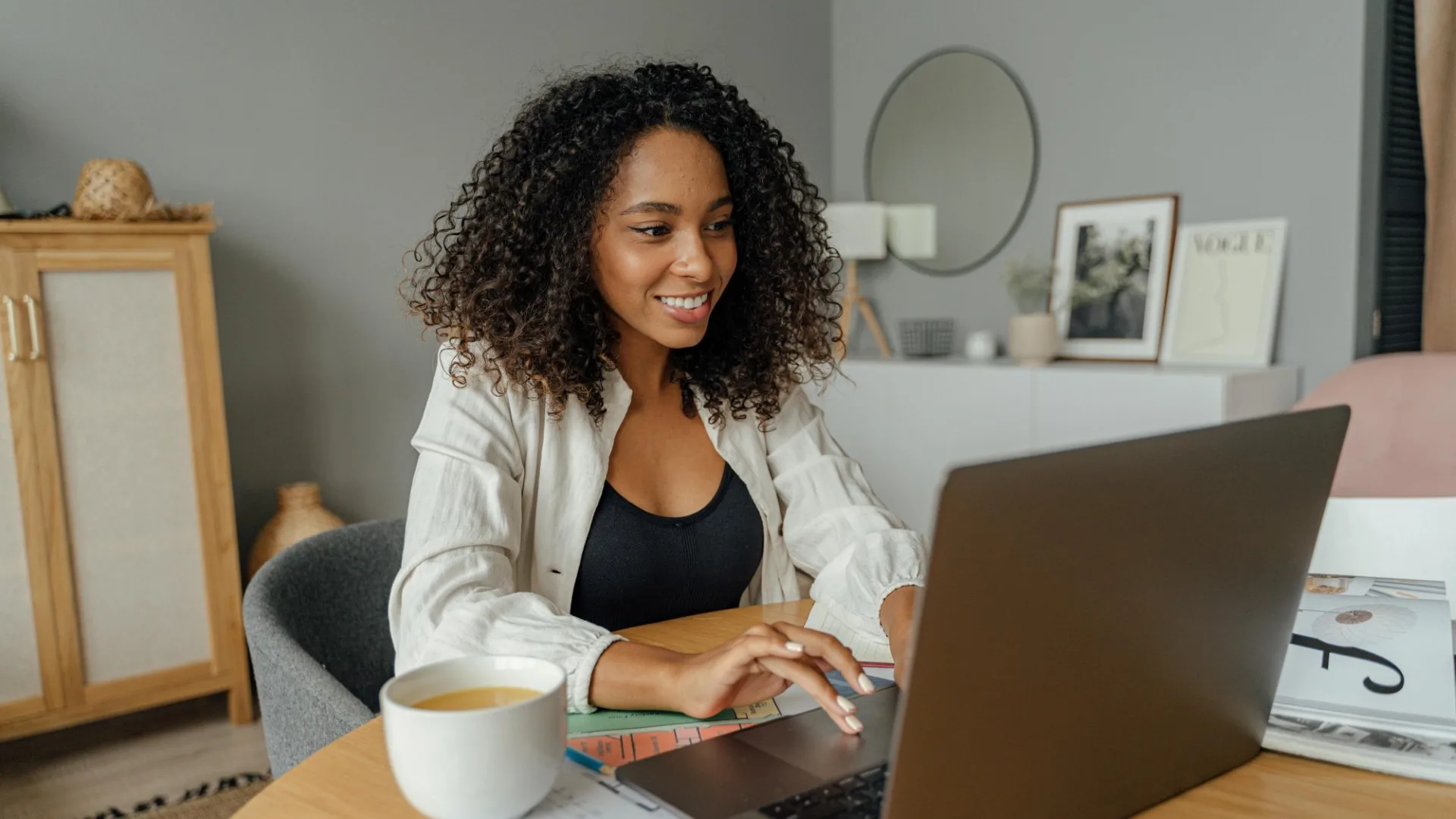 Smiling woman in a cozy living room using a laptop for virtual mental health therapy, representing accessible online support near you
