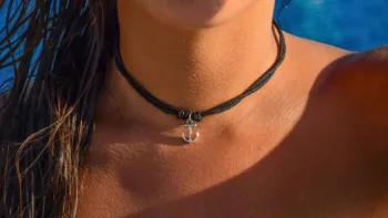 Close-up of a person wearing a black cord necklace with a silver anchor charm, symbolizing grounding and regulation in polyvagal therapy