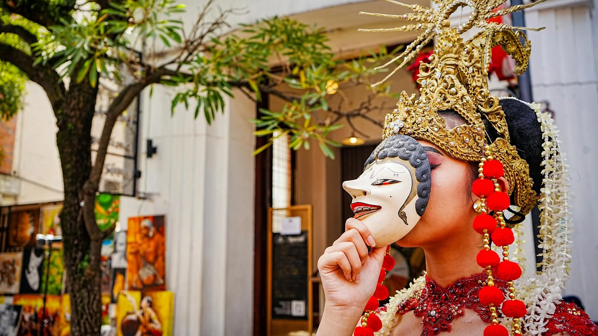 Person in ornate costume holding a mask over their face, symbolizing neurodivergent masking and hidden identity