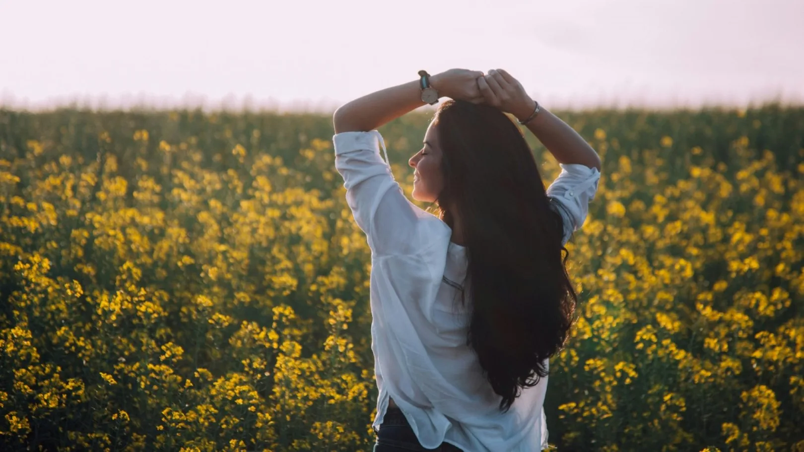 Woman standing in a field at sunset, symbolizing peace after trauma healing therapy in Michigan