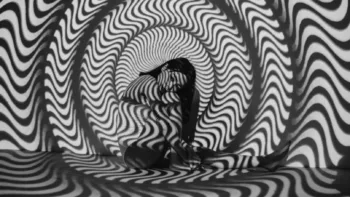 Person seated in a fetal position surrounded by swirling black-and-white hypnotic patterns, symbolizing emotional overwhelm or altered states