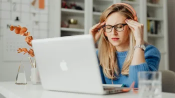 Stressed woman working at laptop, experiencing anxiety and perfectionism at work