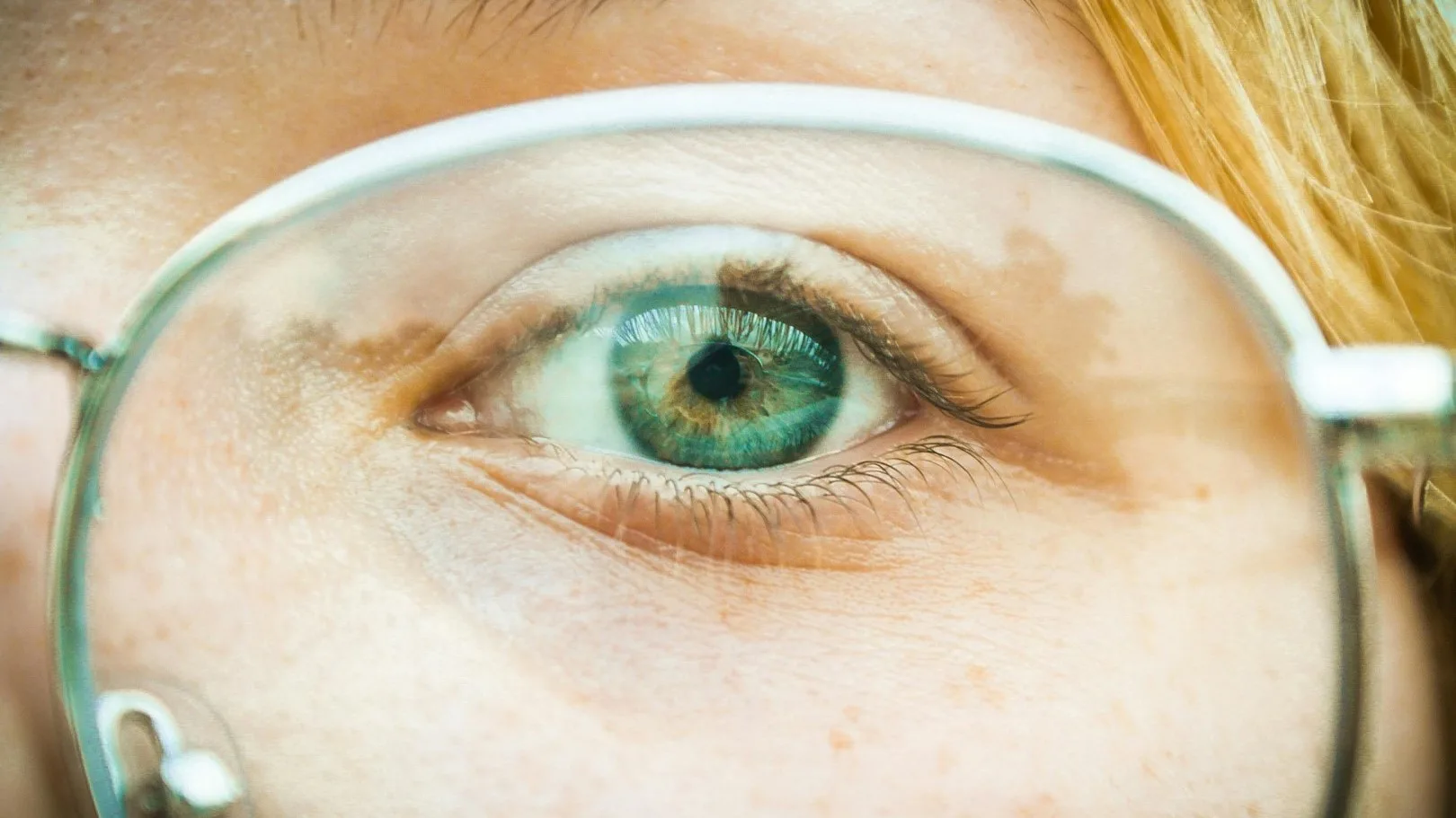 Close-up of a green eye viewed through eyeglasses, symbolizing focus and clarity in EMDR therapy.
