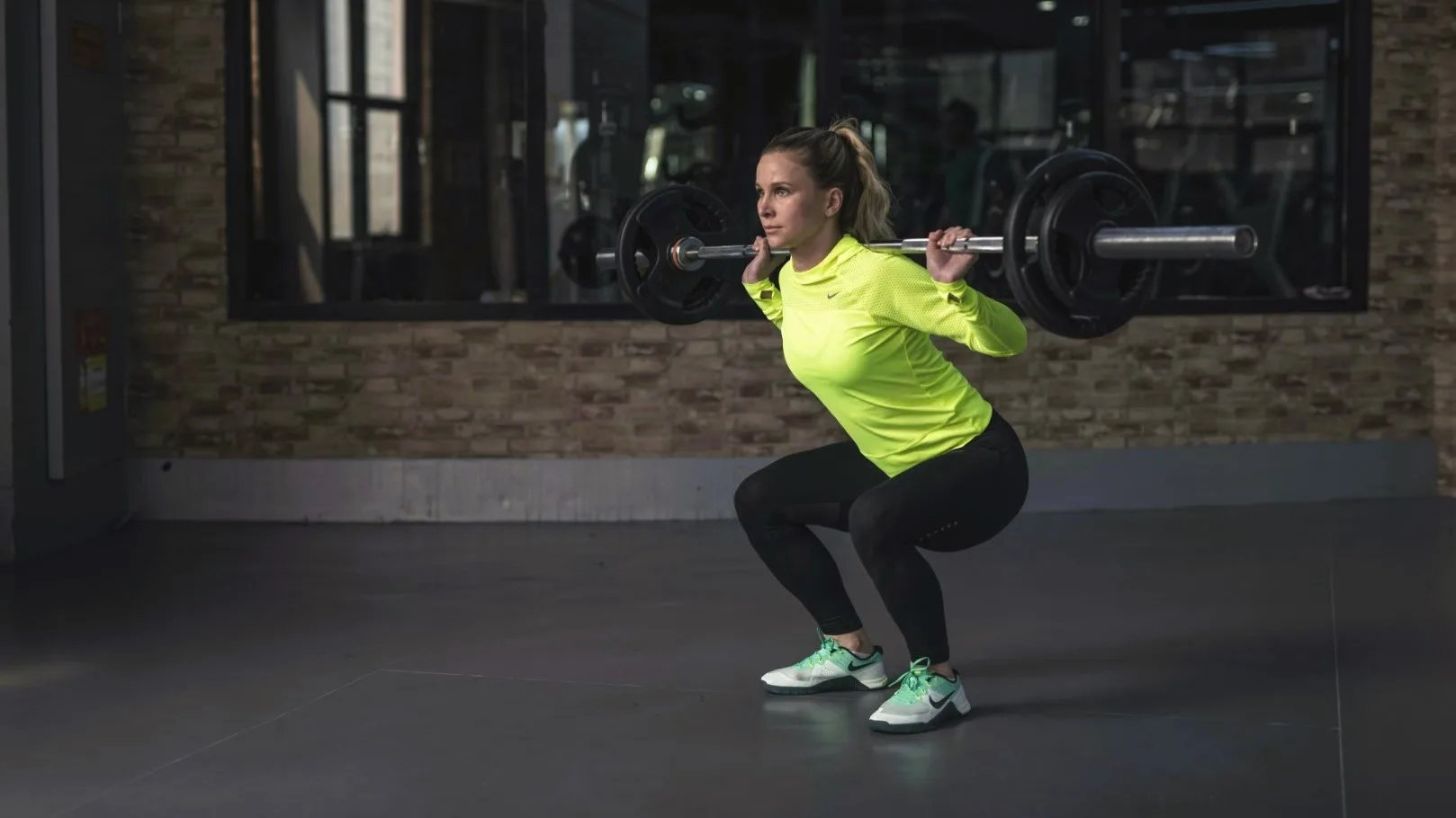 Woman lifting heavy barbell, symbolizing personal growth and resilience through online therapy MI