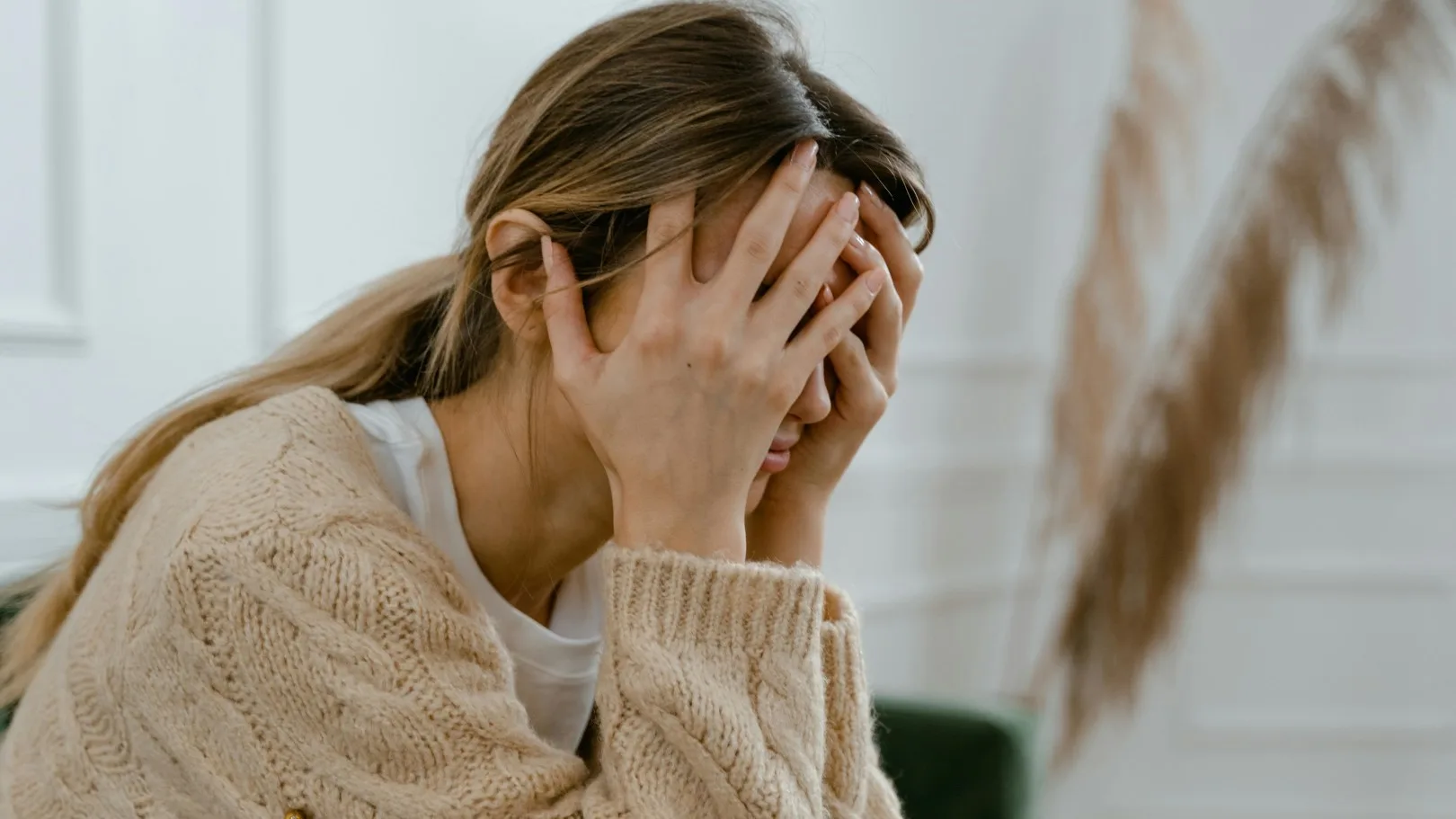 Woman sitting with head in hands, experiencing stress or anxiety