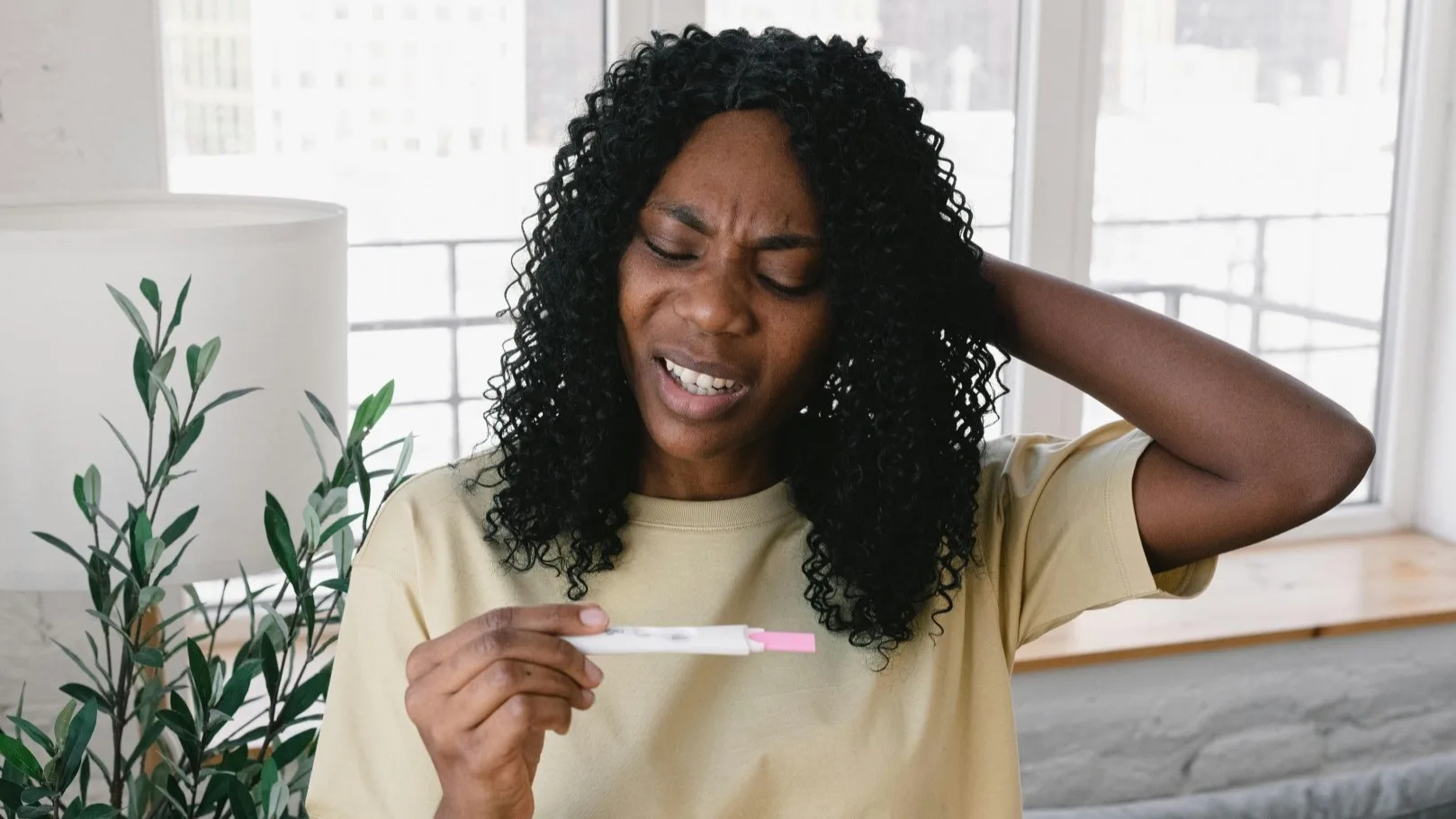 Frustrated woman holding a pregnancy test, expressing confusion and emotional distress