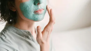 Close-up of a person applying a green facial mask, symbolizing the act of masking mental health struggles.