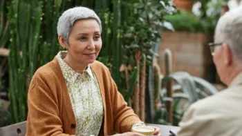Older woman having a warm conversation with another adult outdoors, representing supportive therapy for older adults