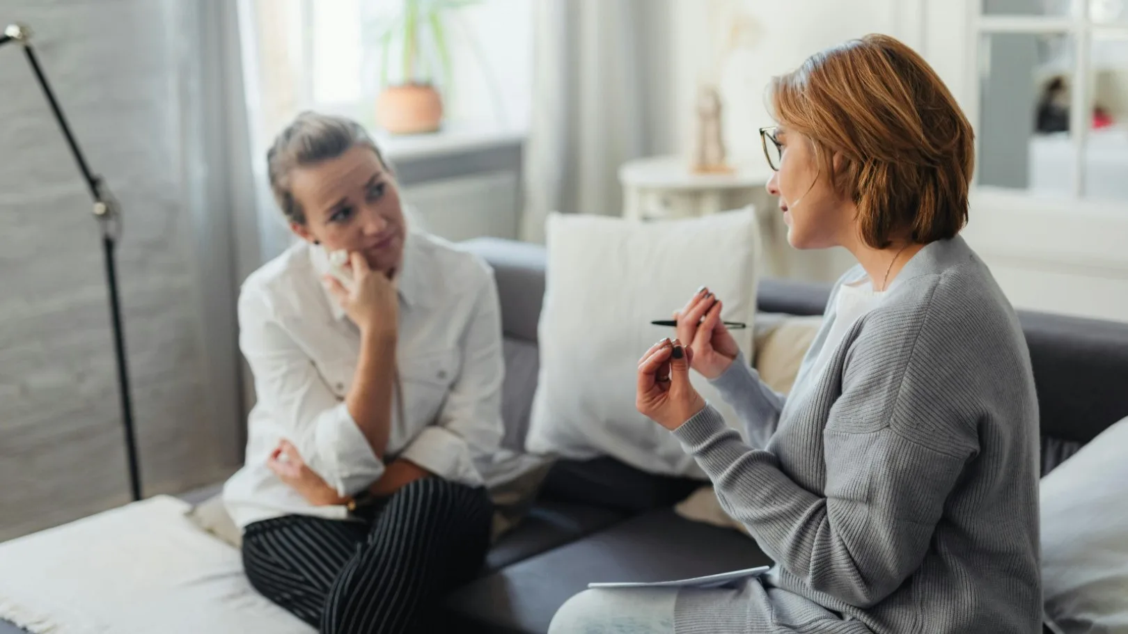 Client having a thoughtful conversation with a new therapist during an initial session in a cozy office setting