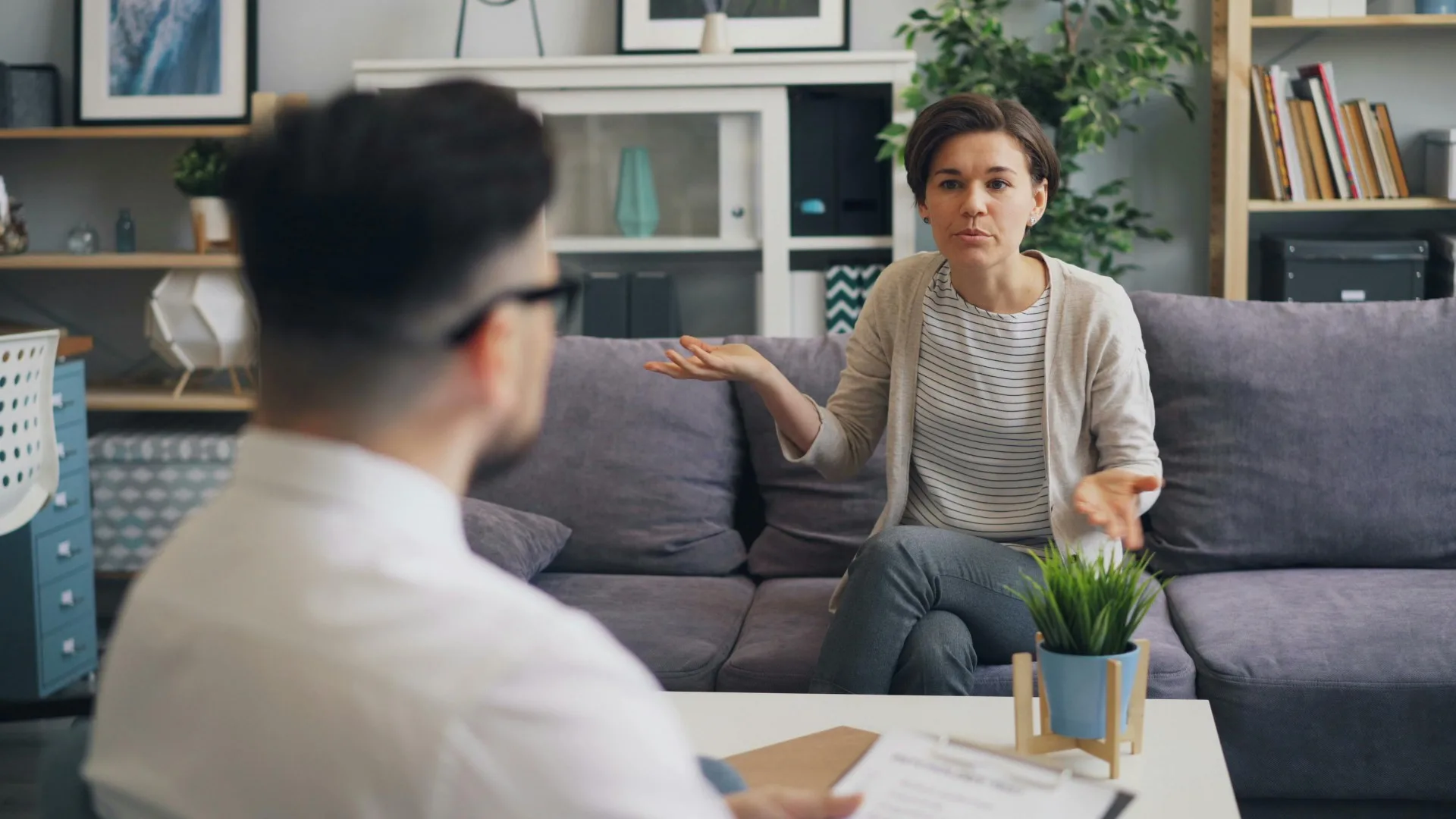 Woman talking to a therapist in a modern counseling office, expressing confusion or seeking clarity
